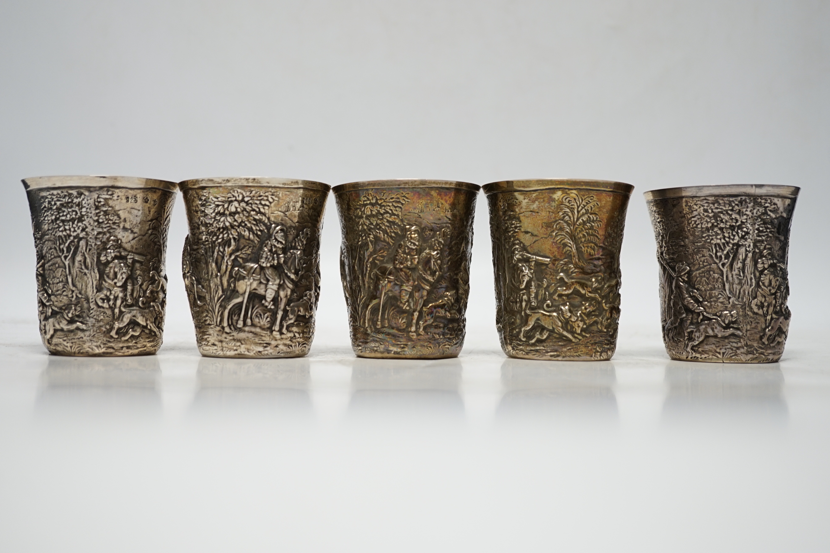 A set of five late 19th century German embossed 925 beakers, decorated with continuous hunting scenes, by Neresheimer Ludwig & Co, 67mm, 16.7oz
